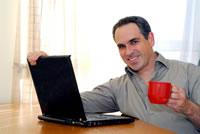 Man at a computer holding a coffee mug